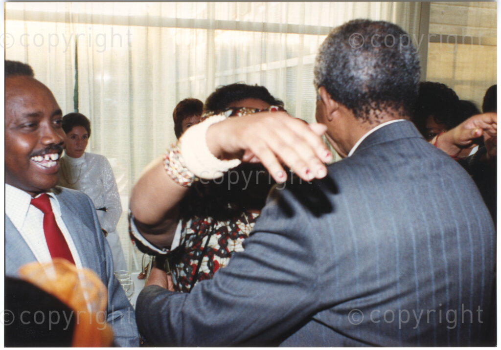 Geneva Ecumenical Centre, Geneva, Switzerland, 19900601. PHOTO: ANC Archives.

A few months after his release from prison, newly elected Deputy President of the African National Congress (ANC) Nelson Mandela and his wife, Winnie Madikizela-Mandela make an official visit to Switzerland, 4-9 June 1990. Shortly after his arrival in Geneva, he visits staff and officials and representatives of the World Council of Churches (WCC) at the Geneva Ecumenical Centre. Surrounded by guests with his back to the camera, an unknown female reaches out to embrace Nelson Mandela.
