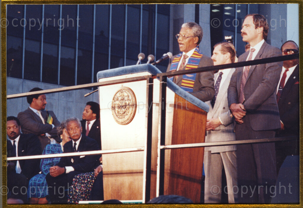 New York, New York State, United States of America, 19900620. PHOTO: ANC Archives.

During Nelson Mandela's Freedom Tour of the United States of America, in June 1990, the core message in each of his speeches, is the need for ongoing financial support of the African National Congress, while at the same time bringing pressure to bear on the apartheid government by maintaining economic, political, cultural and sporting sanctions. Thousands of people attend all his public engagements. Mayor David Dinkins, Mandela's host, is seated on the right of the podium.