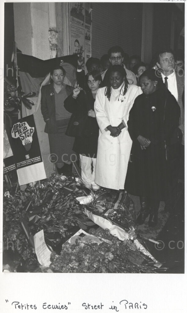Rue des Petites-Ecuries, Paris, Île-de-France, France, 19880301. PHOTO: ANC Archives: People lay wreaths of flowers outside the African National Congress's (ANC) Paris office at 28 Rue des Petites-Ecuries where Dulcie September, a South African anti-apartheid activist and ANC Chief Representative in France, Switzerland and Luxembourg was recently assassinated (on 29 March 1988).