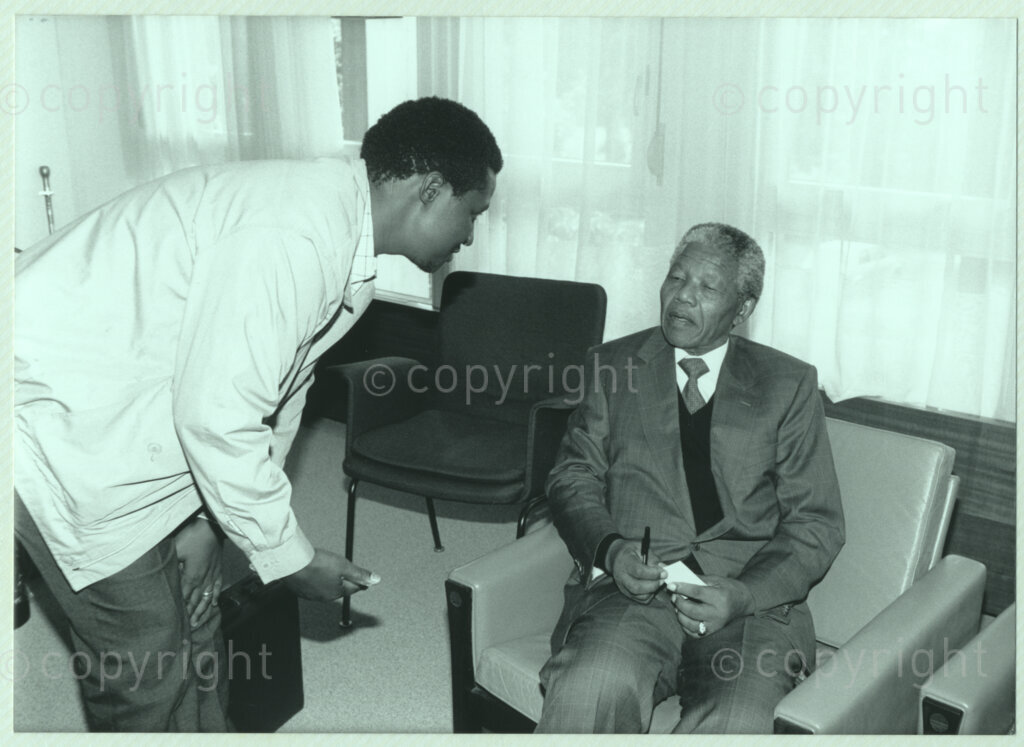 John Knox International Reform Centre, Geneva, Switzerland, 19900609. PHOTO: ANC Archives.

An unidentified male bends down towards recently appointed Deputy President of the African National Congress (ANC) Nelson Mandela who sits in a chair at the International Reformed Centre John Knox (IRCJK), Geneva, Switzerland, 9 June 1990 during Nelson Mandela Mandela's official visit to Switzerland, 4-9 June 1990.