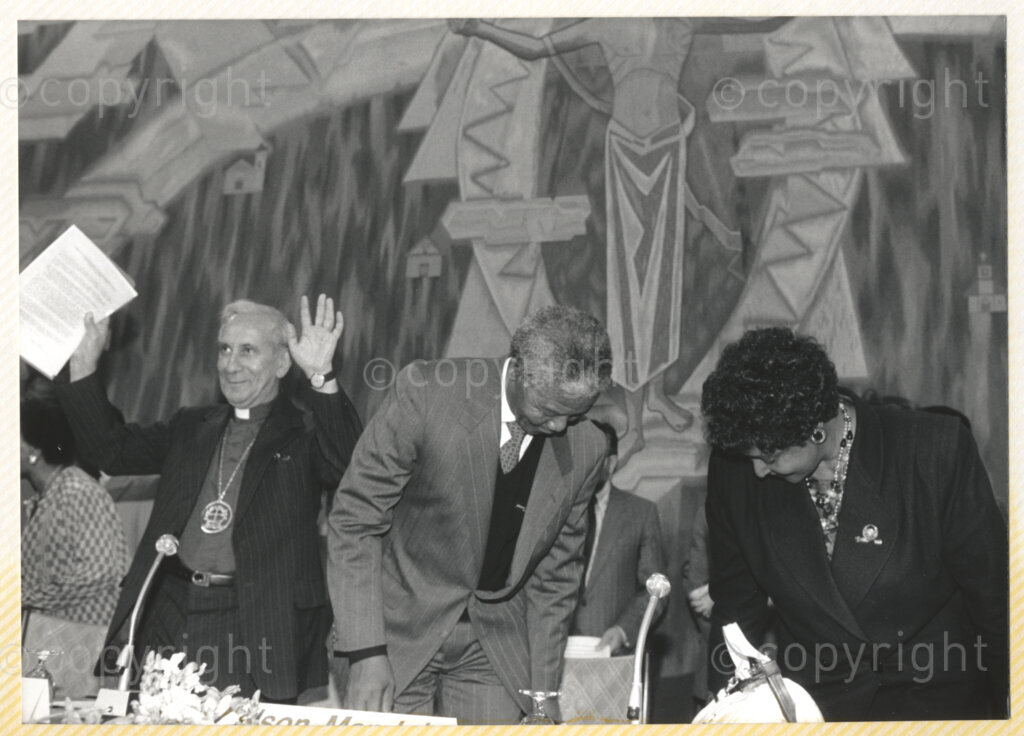 Geneva Ecumenical Centre, Geneva, Switzerland, 19900601. PHOTO: ANC Archives.

General Secretary of the World Council of Churches (WCC) Emilio Castro (left) gestures for the audience to be seated as recently elected Deputy President of the African National Congress (ANC) Nelson Mandela and his wife Winnie Madikizela-Mandela take their seats at the main table at the Geneva Ecumenical Centre, Switzerland when the Mandela couple visit staff, officials and representatives of the WCC during Nelson Mandela's official visit to Switzerland, 4-9 June 1990. During the visit, barely a few months after his release from prison, Nelson Mandela expresses his gratitude to the church for its support of the anti-apartheid struggle.