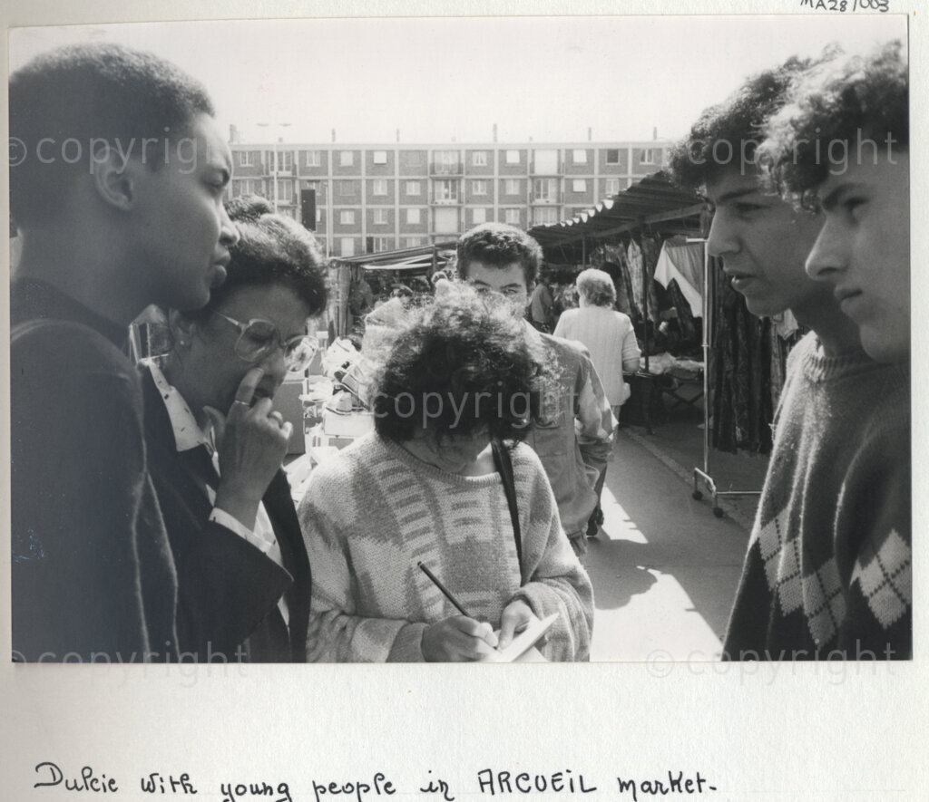 Arcueil, Val-de-Marne, Paris, Île-de-France, France, 1985. PHOTO: ANC Archives: Dulcie September, a South African anti-apartheid activist and African National Congress Chief Representative in France, Switzerland and Luxembourg (second left) with young people in the Arcueil market in Val-de-Marne, Paris, c. 1985. Dulcie September was assassinated outside the ANC's Paris office at 28 Rue des Petites-Ecuries on 29 March 1988.