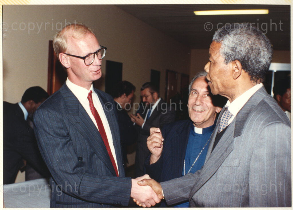 World Council of Churches, Geneva, Switzerland, 19900601. PHOTO: ANC Archives.

Norwegian priest and organizational leader Trond Bakkevig (left) greets Deputy President of the African National Congress (ANC), Nelson Mandela (right) General Secretary of the World Council of Churches (WCC) Emilio Castor stands (centre) at the Geneva Ecumenical Switzerland when the Mandela couple visit staff, officials and representatives of the (WCC) during Nelson Mandela's official visit to Switzerland, 4-9 June 1990. During the visit, barely a few months after his release from prison, Nelson Mandela expresses his gratitude to the church for its support of the anti-apartheid struggle.