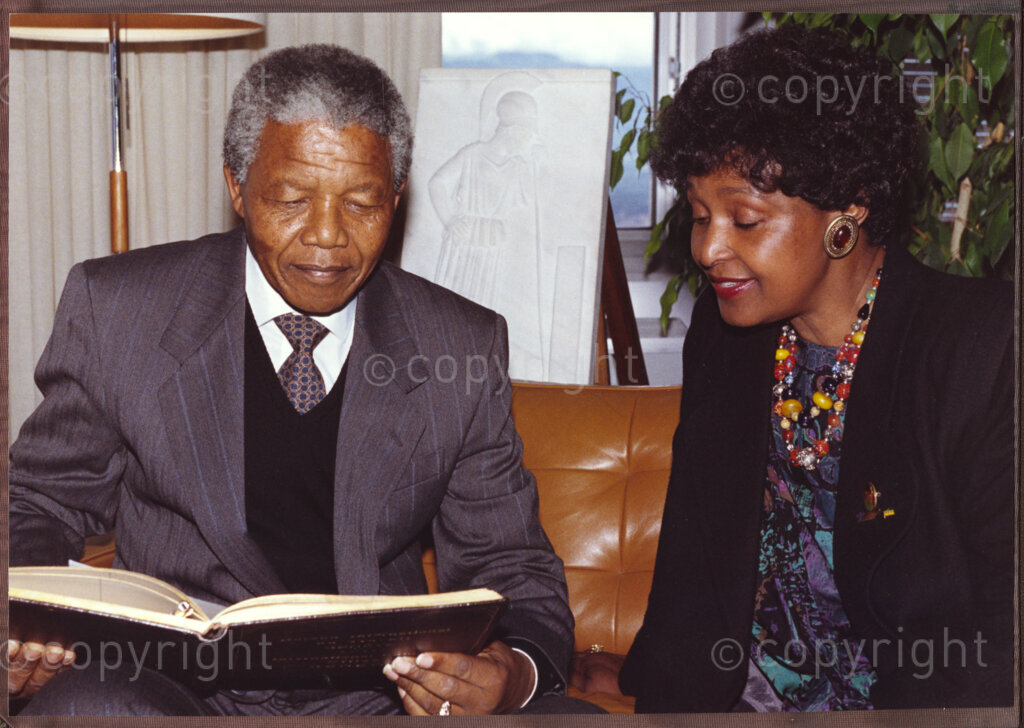 International Labour Organisation, Geneva, Switzerland, 19900608. PHOTO: ANC Archives.

Barely four months after his release from 27 years in prison the deputy president of the African National Congress (ANC), Nelson Mandela and his spouse Winnie Madikizela-Mandela embark on an official visit to Switzerland, 4-9 June 1990. Sitting comfortably in a lounge, paging through a book at the International Labour Organisation (ILO) Nelson Mandela (left) and Winnie Madikizela-Mandela (right). On this occasion, Nelson Mandela delivers his addresses to the 77th Session of the International Labour Conference (ILC), 8 June 1990 where he expresses his gratitude for the support received from the ILO and urges the international community to persist in their demands that all political prisoners must be released, political trials ended, exiles returned, repressive legislation repealed, and the state of emergency ended in its entirety.