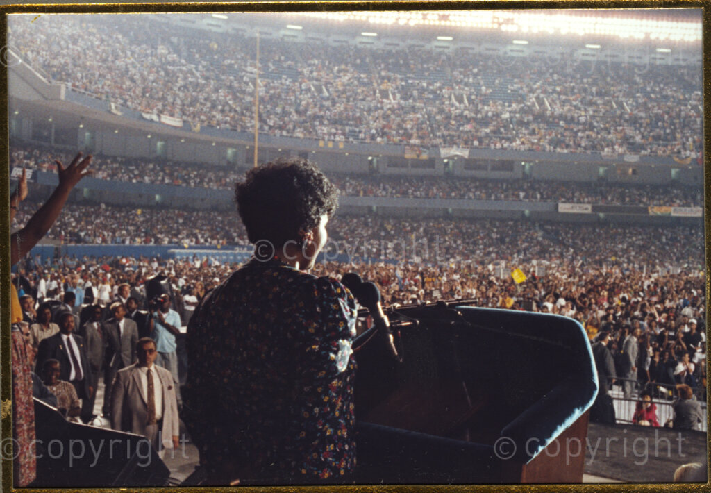 New York, New York State, United States of America, 19900601. PHOTO: ANC Archives.

In June 1990, Nelson and Winnie Mandela embarked on a 14-nation Freedom Tour to celebrate Mandela's release from prison. In New York, in the United States of America, Winnie, herself a fearless anti-apartheid activist, takes to the stage to address the throngs of people. She is seen here giving an address in Harlem, at a rally which is held to honour Nelson Mandela.