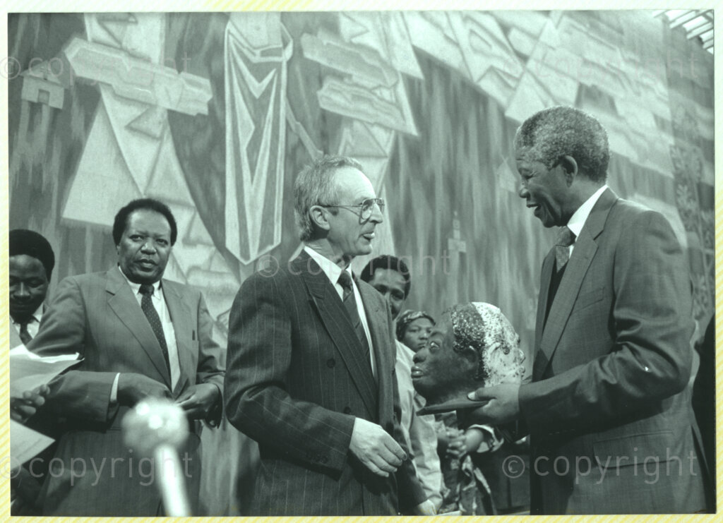 Geneva Ecumenical Centre, Geneva, Switzerland, 19900601. PHOTO: ANC Archives.

Standing on stage (second right) author James Chamunorwa Mutambirwa, recently elected Deputy President of the African National Congress (ANC) Nelson Mandela (right) who accepts a sculpture from an unidentified official (centre) at the Geneva Ecumenical Centre, Switzerland when the Mandela couple visit staff, officials and representatives of the World Council of Churches (WCC) during Nelson Mandela's official visit to Switzerland, 4-9 June 1990. During the visit, barely a few months after his release from prison, Nelson Mandela expresses his gratitude to the church for its support of the anti-apartheid struggle.