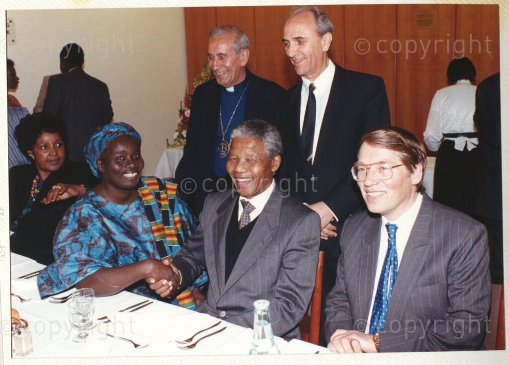 Geneva Ecumenical Centre, Geneva, Switzerland, 19900601. PHOTO: ANC Archives.

A few months after his release from prison, newly elected Deputy President of the African National Congress (ANC) Nelson Mandela and his wife, Winnie Madikizela-Mandela pay an official visit to Switzerland, 4-9 June 1990. Shortly after his arrival in Geneva, he visits officials and staff members of the World Council of Churches (WCC) and other organisations at the Geneva Ecumenical Centre. Seated in a group (left to right) Winnie Madikizela-Mandela, Ghanaian Methodist theologian Mercy Amba Oduyoye, Nelson Mandela and the general secretary of the Lutheran World Federation Gunnar Johan Stålsett. An unidentified male guest and General Secretary of the WCC Emilio Castro (left) stand in the back row. During this visit, Nelson Mandela expresses his gratitude to the church for its support of the anti-apartheid struggle.
