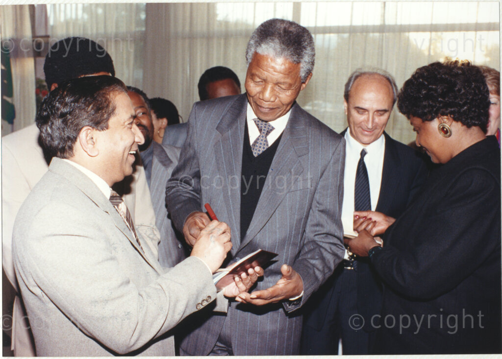 Geneva Ecumenical Centre, Geneva, Switzerland, 19900601. PHOTO: ANC Archives.

A few months after his release from prison, newly elected deputy president of the African National Congress (ANC) Nelson Mandela and his wife, Winnie Madikizela-Mandela pay an official visit to Switzerland, 4-9 June 1990. Shortly after his arrival in Geneva, he visits the staff and officials and representatives of the World Council of Churches (WCC) at the Geneva Ecumenical Centre. Standing amongst a group of guests, Nelson Mandela (centre) signs an autograph for theologian and former director of inter-religious relations at the WCC Wesley Ariarajah while Winnie Madikizela-Mandela with her back to the camera (right) signs an autograph for an unknown guest.