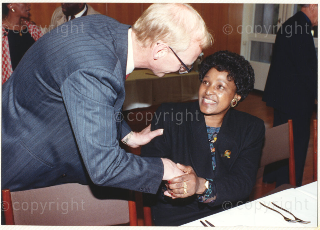 Geneva Ecumenical Centre, Geneva, Switzerland, 19900601. PHOTO: ANC Archives.

An unknown guest bends down to greet Winnie Madikizela-Mandela seated at a dinner table at the time of Nelson Mandela's visit to staff and officials and representatives of the World Council of Churches (WCC) at the Geneva Ecumenical Centre, 4-9 June 1990. During this visit, Nelson Mandela expresses his gratitude to the church for its support of the anti-apartheid struggle.