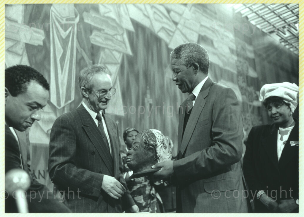 Geneva Ecumenical Centre , Geneva, Switzerland, 19900601. PHOTO: ANC Archives.

Standing on stage (second right) author James Chamunorwa Mutambirwa, recently elected Deputy President of the African National Congress (ANC) Nelson Mandela (right) who accepts a sculpture from an unidentified official (centre) at the Geneva Ecumenical Centre, Switzerland when the Mandela couple visit staff, officials and representatives of the World Council of Churches (WCC) during Nelson Mandela's official visit to Switzerland, 4-9 June 1990. During the visit, barely a few months after his release from prison, Nelson Mandela expresses his gratitude to the church for its support of the anti-apartheid struggle.