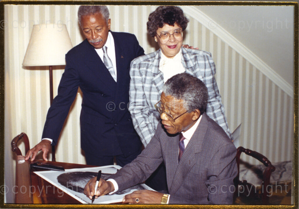New York, New York State, United States of America, 19900620. PHOTO: ANC Archives.

Nelson Mandela and his wife, Winnie, are on a 14-nation Freedom Tour in June 1990, just four months after his release from prison. In New York, in the United States of America, Mayor David N. Dinkins and his wife, Joyce, are the Mandela's hosts. Dinkins is the first black mayor of New York City. The mayoral couple look on as Mandela signs what appears to be a poster-portrait of himself.