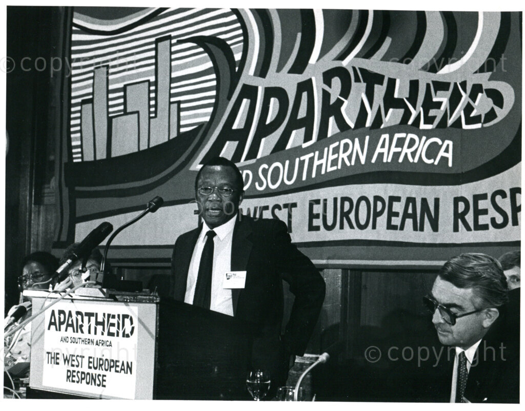 Conference by the Holland Committee on Southern Africa and AWEPAA in the Amsterdam City Hall, September 1985; speaker: Johnny Makatini (ANC); right: AWEPAA chair Jan-Nico Scholten. Photographer: Loes van den Bergh.
