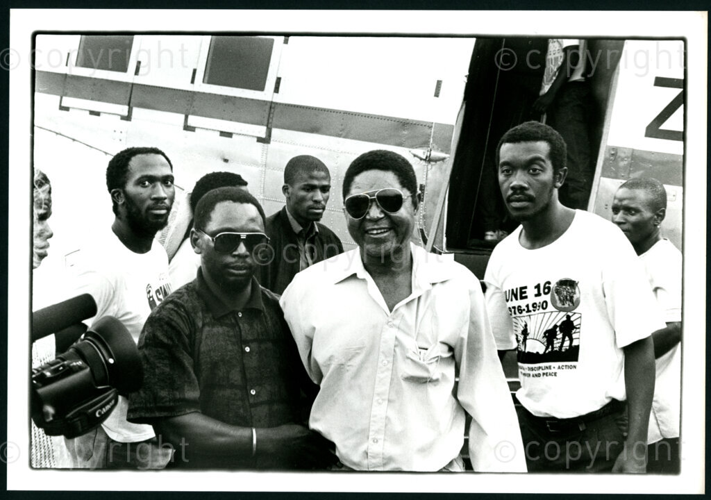 Duckmore Mthimkhulu (centre); alias Morris. Disabled ANC member in exile, arrives on the airport of Umtata on his return to South Africa in November 1990. Photographer: Pieter Boersma.