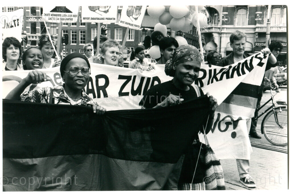 South African Women's Day demonstration in Amsterdam, 9 August 1986; in front, with ANC-flag: Shirley Masiane (left) and Buni Sechwale (right) - both ANC Women's Section. Photographer: Inge Goijaerts.