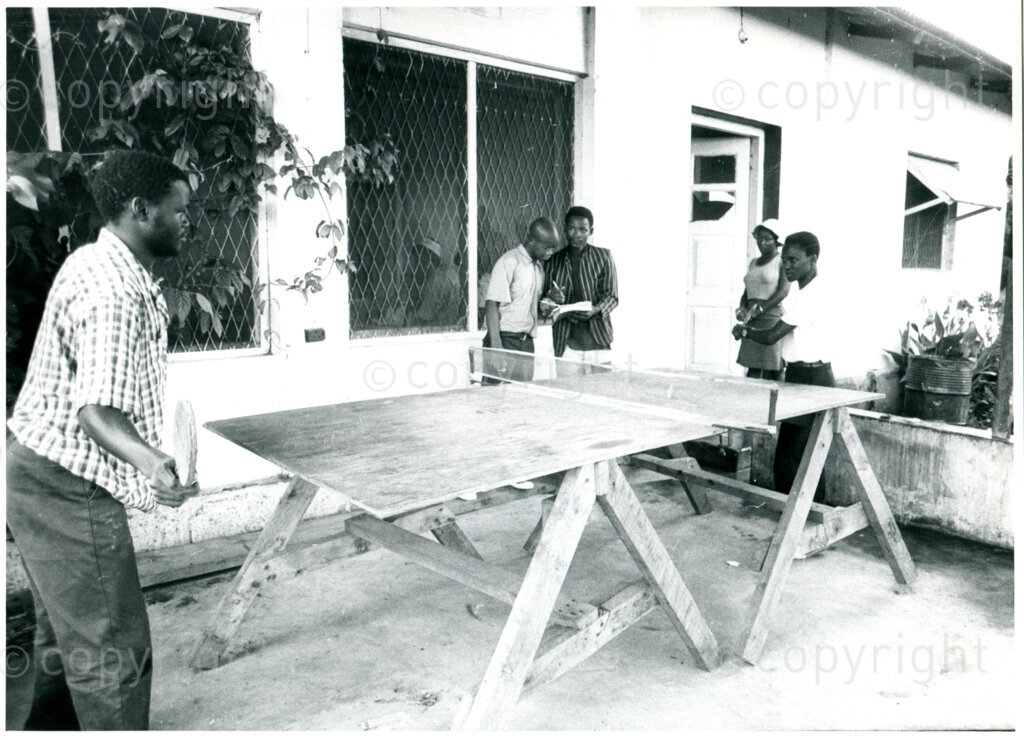 Students playing table tennis outside one of the old houses in Mazimbu, Tanzania, 1979. Photographer: Eli Weinberg.
