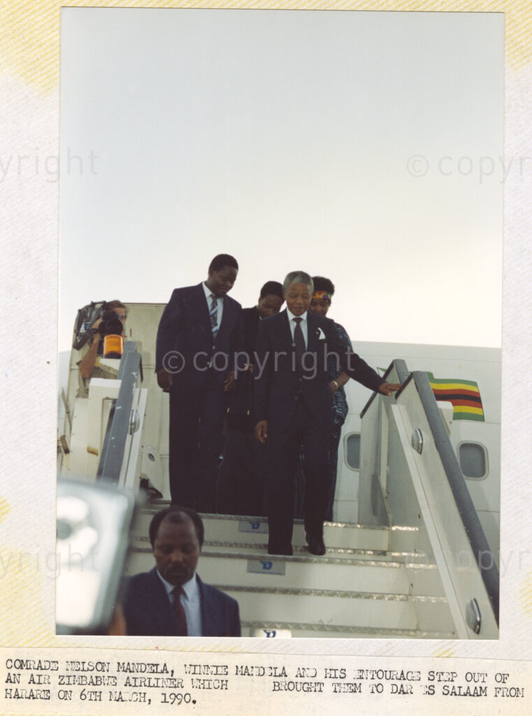 Dar Es Salaam, Tanzania. PHOTO: ANC Archives. 6 March 1990. Nelson Mandela, deputy president of the African National Congress (ANC), (centre front), emerges from an Air Zimbabwe flight, with his entourage, in Dar Es Salaam. They are met by an enormous crowd of supporters, admirers and ANC members, in Tanzania. Mandela and his wife, Winnie are on a tour of African states which support the liberation struggle of South Africa. It is just one month since Mandela was released from prison.