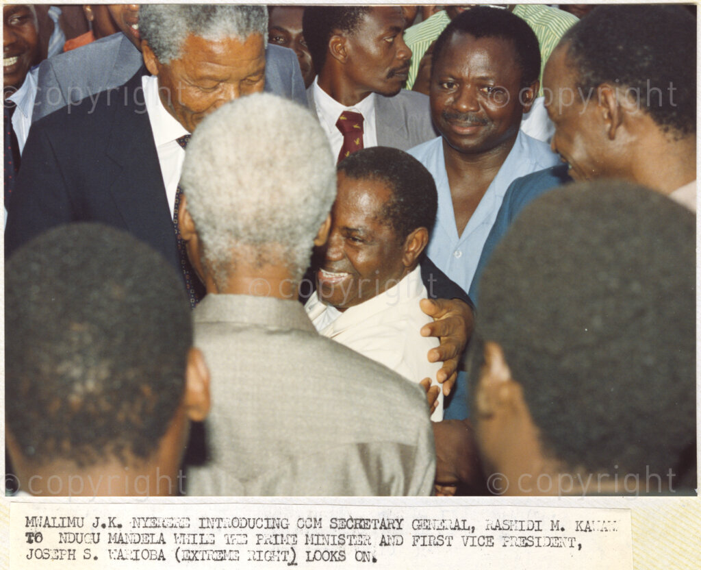Dar Es Salaam, Tanzania. PHOTO: ANC Archives. 6 March 1990. At Dar Es Salaam International Airport in Tanzania, Julius Nyerere (grey hair, back to camera), chairman of the Chama Cha Mapinduzi (CCM), introduces CCM Secretary General Rahidi M Kawawa to Nelson Mandela who wears a dark suit, while Joseph S Waioba (extreme right), prime minister and first vice president, looks on. Nelson and Winnie Mandela are on a tour of African states which support the liberation struggle in South Africa. It is just one month since Mandela was released from prison.