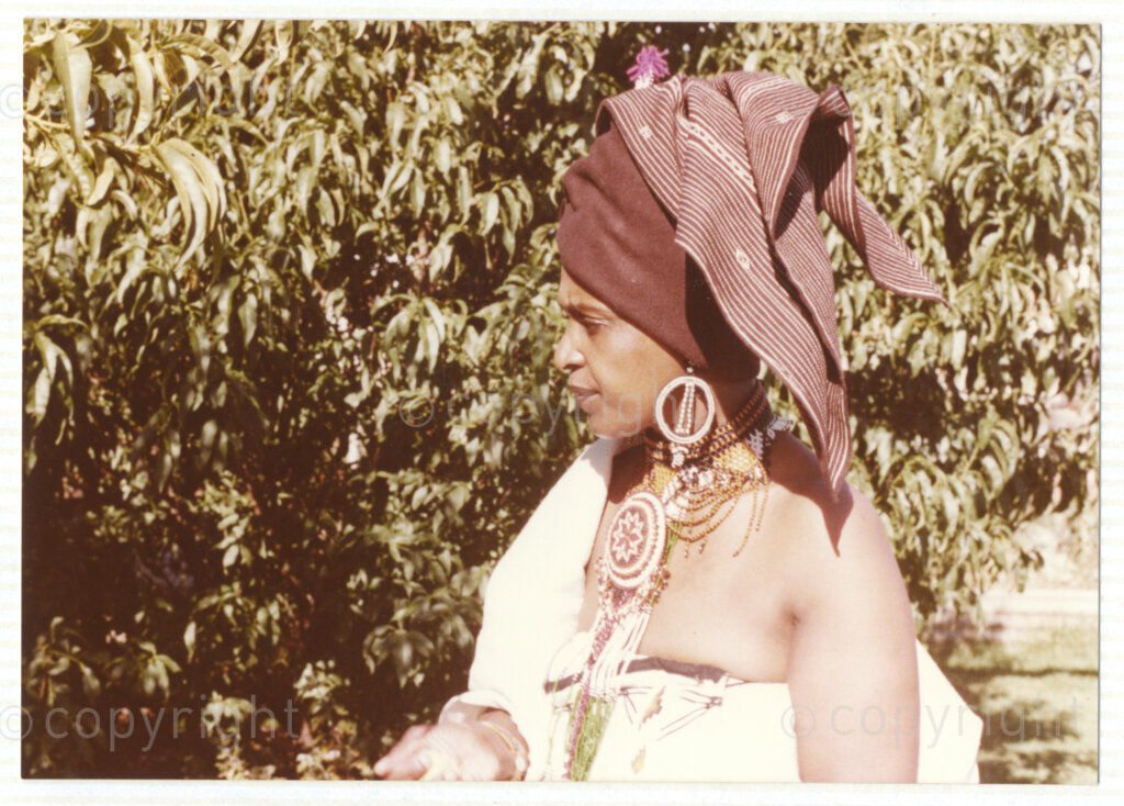 A portrait of Winnie Mandela wearing traditional Xhosa attire, circa 1980. She was one of the most important icons of the struggle against apartheid in South Africa and wore traditional outfits and accessories during a time when donning cultural wear was seen as a political taboo. The outfit reflects the cultural heritage of her birthplace, Bizana, a rural town in the Transkei in the Eastern Cape.