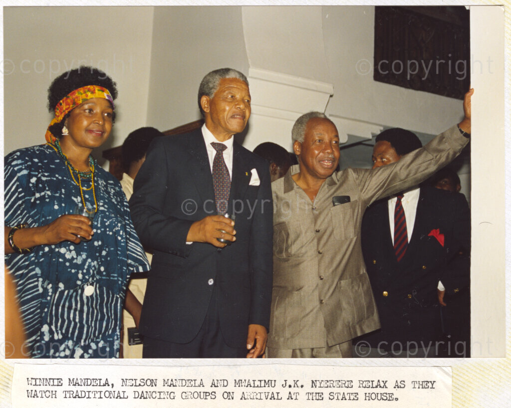 Dar Es Salaam, Tanzania. PHOTO: ANC Archives. 6 March 1990. Winnie Mandela (left), Nelson Mandela (centre) and host, Julius Nyerere relax as they enjoy an item of traditional dancing on the Mandela's arrival at the State House, Dar Es Salaam, Tanzania. The Mandelas are on a tour of African states which support the liberation struggle in South Africa.