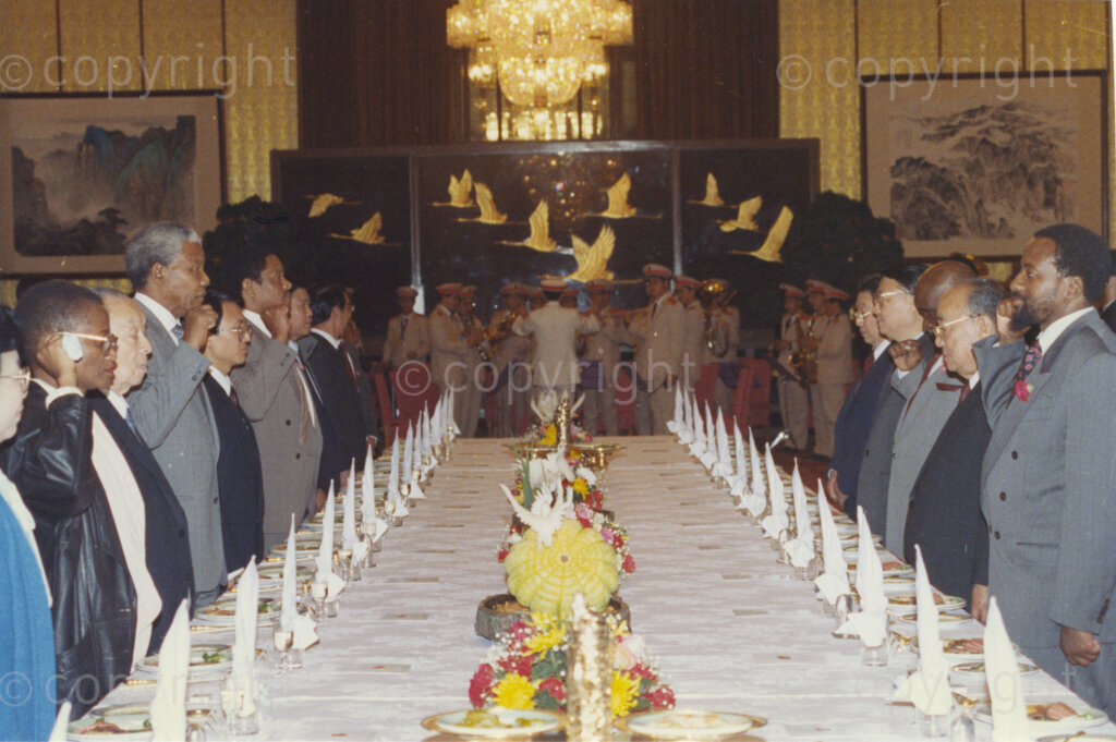 The Great Hall of the People, Beijing, Beijing Municipality, People's Republic of China , 19921005. PHOTO: ANC Archives.

The President of the African National Congress, Nelson Mandela (centre left), accompanied by the ANC spokesman, Mr Pallo Jordan (right), visits the People's Republic of China (PRC) in October 1992. At this time South Africa recognises Taiwan (ROC) as independent from the PRC, and Nelson Mandela is in support of a 'Two Chinas' policy. The weeklong visit to China involves discussions towards establishing official ties between a Greater China (including PRC and ROC) and South Africa. A number of welcoming ceremonies are held where the ANC delegates meet with, amongst others, President Yang Shangkun (next to Pallo Jordan), Prime Minister Li Peng and the Chinese Communist Party General Secretary, Jiang Zemin. Press conferences are held at the Great Hall of the People. After many years of strong lobbying by the PRC, and engagement with Nelson Mandela, official relations between the PRC's 'One China' and South Africa were established in 1998.