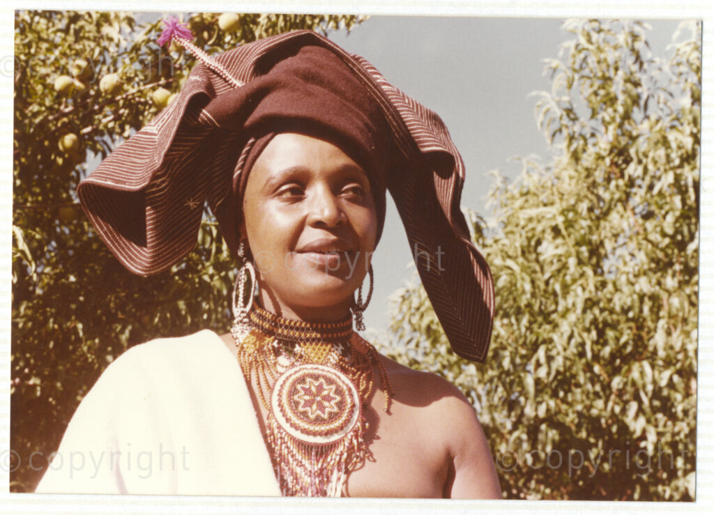A portrait of Winnie Mandela wearing traditional Xhosa attire, circa 1980. She was one of the most important icons of the struggle against apartheid in South Africa and wore traditional outfits and accessories during a time when donning cultural wear was seen as a political taboo. The outfit reflects the cultural heritage of her birthplace, Bizana, a rural town in the Transkei in the Eastern Cape.