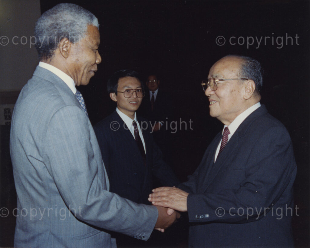 The Great Hall of the People, Beijing, Beijing Municipality, People's Republic of China , 19921005. PHOTO: ANC Archives.

The President of the African National Congress, Nelson Mandela (left), accompanied by the ANC spokesman, Mr Pallo Jordan visits the People's Republic of China (PRC) in October 1992. At this time South Africa recognises Taiwan (ROC) as independent from the PRC, and Nelson Mandela is in support of a 'Two Chinas' policy. The weeklong visit to China involves discussions towards establishing official ties between a Greater China (including PRC and ROC) and South Africa. A number of welcoming ceremonies are held where the ANC delegates meet with, amongst others, President Yang Shangkun (right), Prime Minister Li Peng and the Chinese Communist Party General Secretary, Jiang Zemin. After many years of strong lobbying by the PRC, and engagement with Nelson Mandela, official relations between the PRC's 'One China' and South Africa were established in 1998.