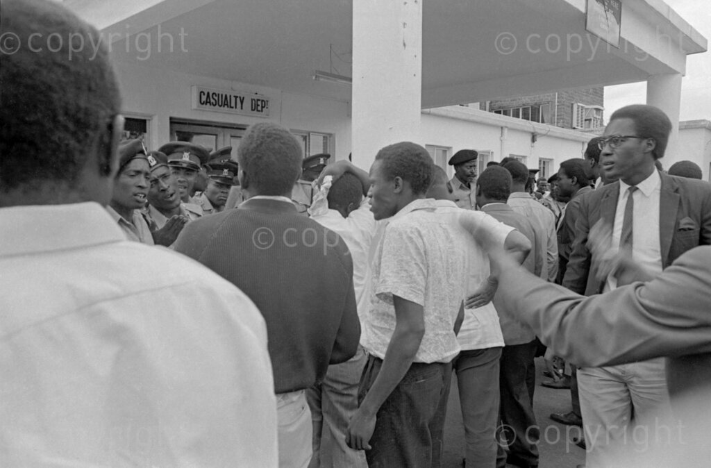 Kenyans anxiously gather outside the hospital, hoping for news after Tom Mboya was rushed in following the tragic shooting.