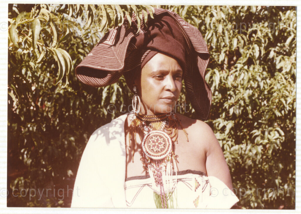 A portrait of Winnie Mandela wearing traditional Xhosa attire, circa 1980. She was one of the most important icons of the struggle against apartheid in South Africa and wore traditional outfits and accessories during a time when donning cultural wear was seen as a political taboo. The outfit reflects the cultural heritage of her birthplace, Bizana, a rural town in the Transkei in the Eastern Cape.