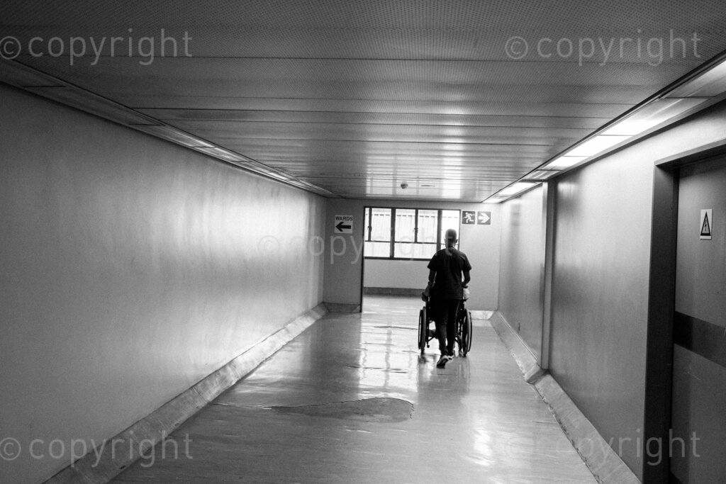 A physiotherapist wheels a patient back to her ward down a corridor in this vast health facility. 22, 23, Feb. 2024, Pietermaritzburg, KwaZulu Natal, South Africa.