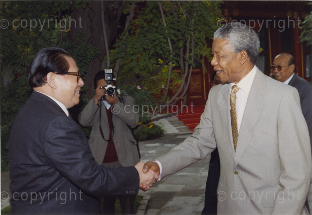 Great Hall of the People , Beijing, Beijing Municipality, People's Republic of China , 19921005. PHOTO: ANC Archives.

The President of the African National Congress, Nelson Mandela, accompanied by the ANC spokesman, Mr Pallo Jordan visits the People's Republic of China (PRC) in October 1992. At this time South Africa recognises Taiwan (ROC) as independent from the PRC, and Nelson Mandela is in support of a 'Two Chinas' policy. The weeklong visit to China involves discussions towards establishing official ties between a Greater China (including PRC and ROC) and South Africa. A number of ceremonies are held where the ANC delegates meet with, amongst others, President Yang Shangkun, Prime Minister Li Peng and the Chinese Communist Party General Secretary, Jiang Zemin. Mr Zemin (left) greets Mr Mandela (right) at the welcoming ceremony at the Great Hall of the People in Beijing on the 5 October 1993. After many years of strong lobbying by the PRC, and engagement with Nelson Mandela, official relations between the PRC's 'One China' and South Africa were established in 1998.
