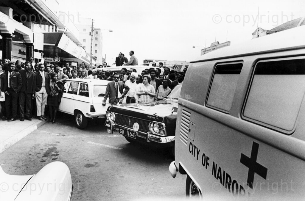 The suddenness of the attack on Tom Mboya left everyone in shock, and the bustling city center was immediately thrown into chaos. As news of the shooting spread, a crowd quickly gathered outside the pharmacy. The atmosphere was tense, with people crying out in disbelief and anger.