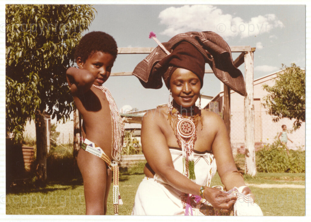 Winnie Mandela (right) and a young child (unknown), both wearing traditional Xhosa attire, circa 1980. Mandela was one of the most important icons of the struggle against apartheid in South Africa and wore traditional outfits and accessories during a time when donning cultural wear was seen as 
a political taboo. The outfits reflect the cultural heritage of her birthplace, Bizana, a rural town in the Transkei in the Eastern Cape.