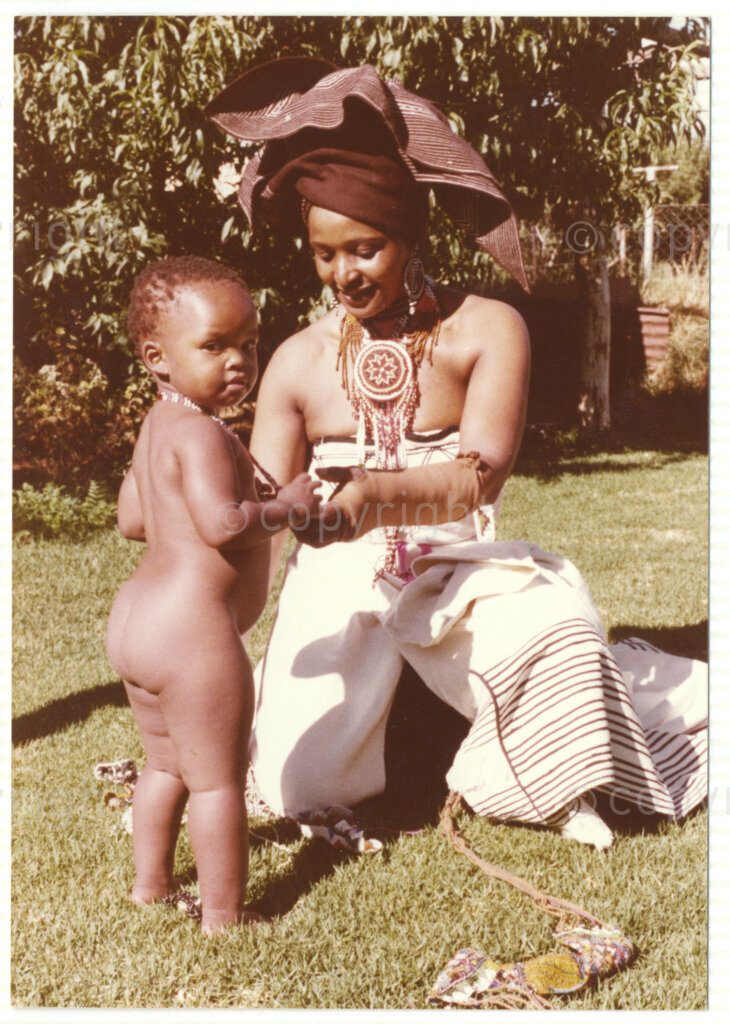 Winnie Mandela (right) and a young child (unknown), both wearing traditional Xhosa attire, circa 1980. Mandela was one of the most important icons of the struggle against apartheid in South Africa and wore traditional outfits and accessories during a time when donning cultural wear was seen as 
a political taboo. The outfits reflect the cultural heritage of her birthplace, Bizana, a rural town in the Transkei in the Eastern Cape.