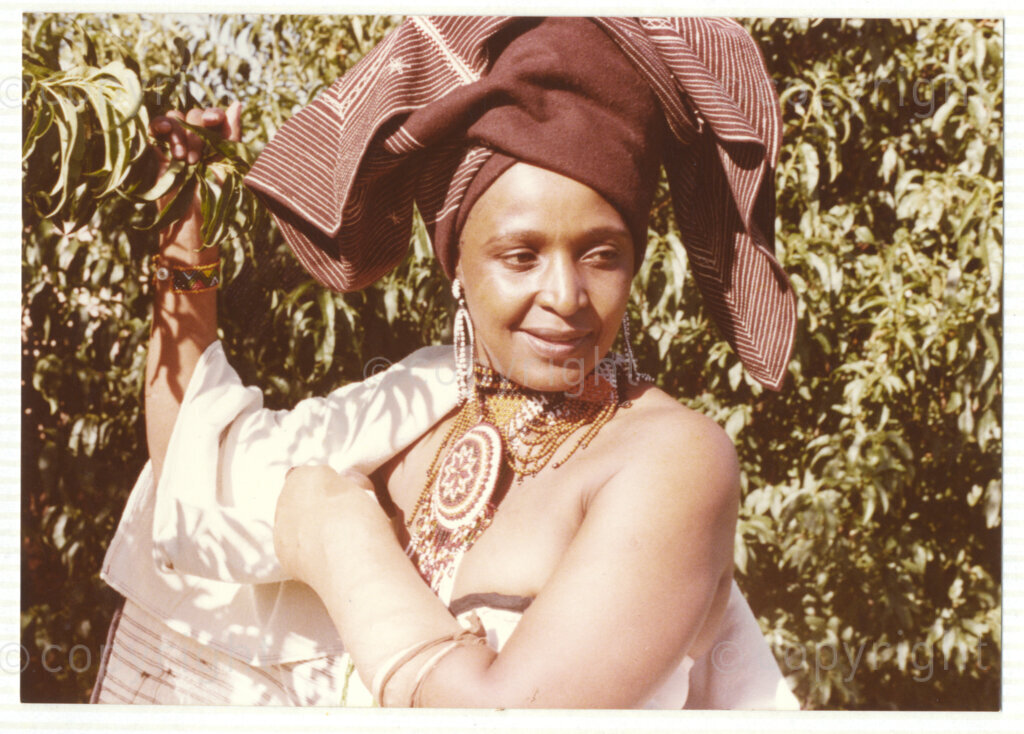 A portrait of Winnie Mandela wearing traditional Xhosa attire, circa 1980. She was one of the most important icons of the struggle against apartheid in South Africa and wore traditional outfits and accessories during a time when donning cultural wear was seen as a political taboo. The outfit reflects the cultural heritage of her birthplace, Bizana, a rural town in the Transkei in the Eastern Cape.