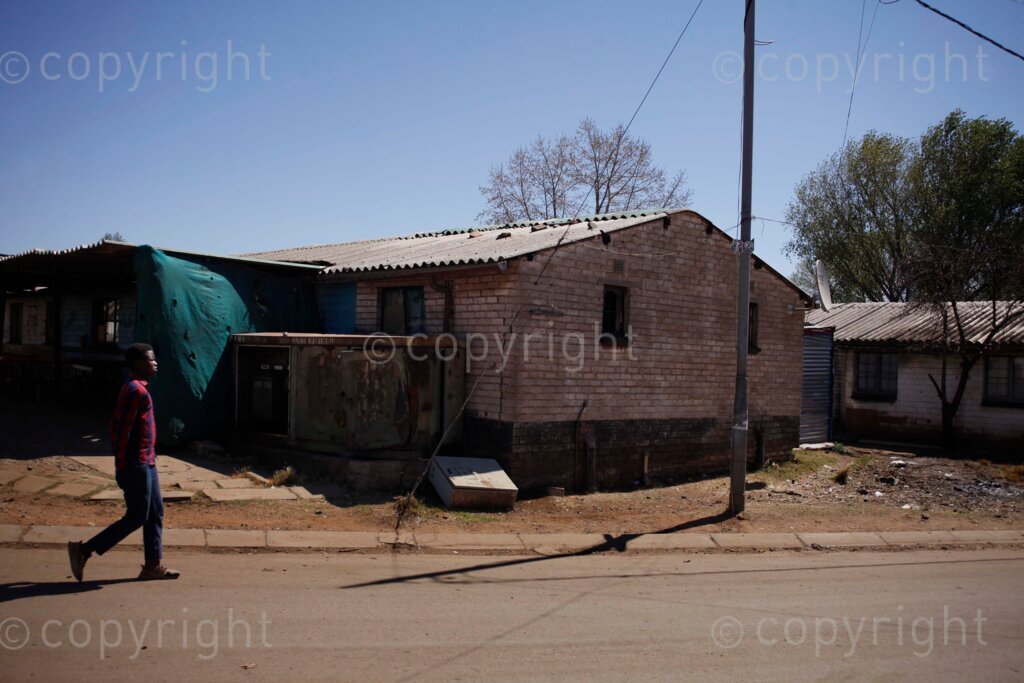 A man walking pass an electric box that has exploded and has not been supplying electricity for about three months to the affected blocks of rooms at the Nancefield Hostel in Klipstruit, Soweto, south west of Johannesburg in Gauteng, South Africa. This has caused the affected residents to protest on the streets. 31/08/21 Photo: Oupa Nkosi 