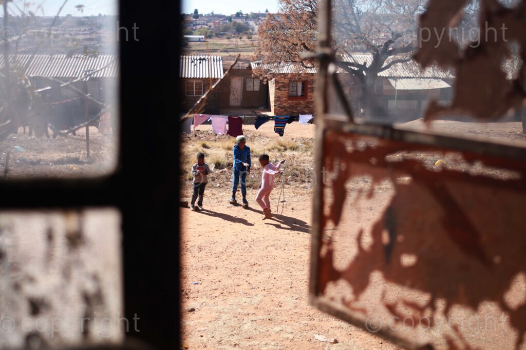 A view from the window room of children playing outside at the Diepkloof hostel in Soweto, south west of Johannesburg in Gauteng, South Africa. 11 July 2023 Photo: Oupa Nkosi
