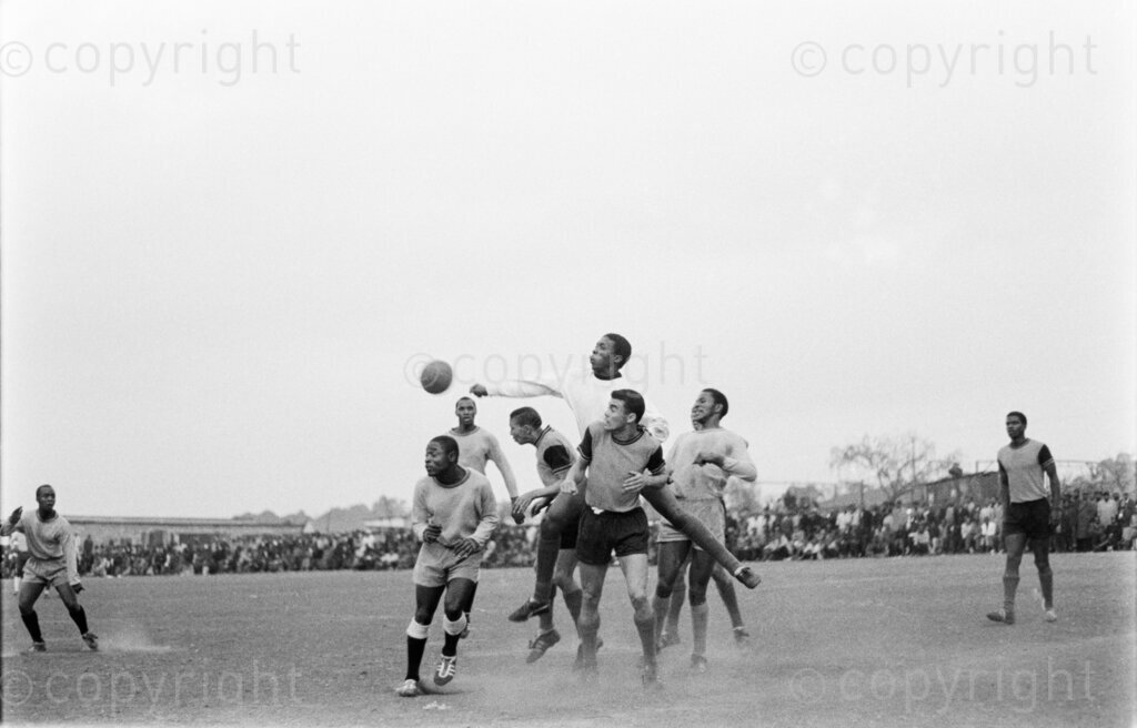 Orlando Pirates and Moroka Swallows combined team Vs Rest at Kliptown Stadium. Ronnie Hilita, goalkeeper of the Rest, punches the ball clear during a melee at the poles. Other players in the picture are Kaizer Motaung, Mandla Mabaso (extreme left), Mainline Khoza (behind), Royston Alfreds (appearing to head) and Richard Wilskut (facing camera).