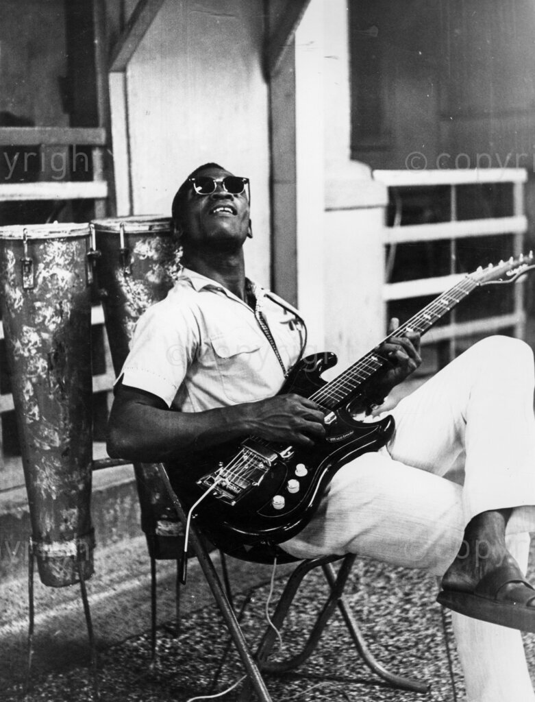 Guitar Man John Akwaboa. He is sitting and playing his guitar. John Akwaboa's name is musical magic. In Ghana this guitarist commands tremendous following. Almost every hotel, night club and bar in Ghana blares out Akwaboa's music. His discs are often hits.