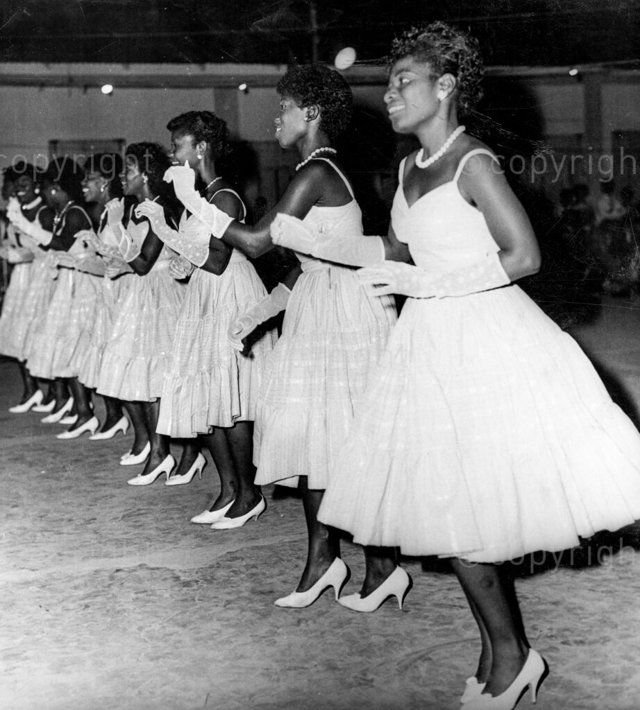 Ghana Learns To Dance – Ready to compete, these girls have become experts in ballroom dancing, and they are now able to compete in dance contests. Foxtrot, tango, waltz, cha cha cha, rock n' roll; it does not matter what is the dance, or whether it is simple or complicated, you can be pretty certain that somewhere in Accra someone is trying to learn the steps. Yes, ballroom dancing is the craze, and everyone's in the swing. If you pop in at any of Accra's night clubs in the early evening, before the real show show of the night comes on, you will find scores of people on the open floor going through a series of amazing movements. And you will find they are learning to dance.