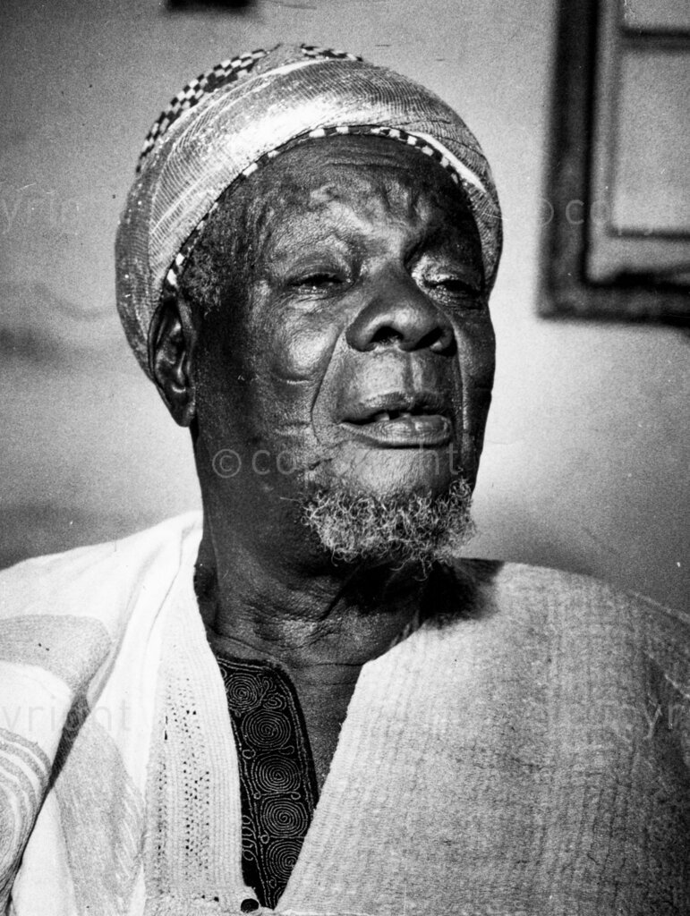 The tragi-comic make-believe palace of a ruler in exile. Portrait of a sad ruler, Alhaji Adeyemi Adeniran. The powerful, greying Yoruba Oba, Alhadji Adeniran, was booted out of his Royal Stool at the age of 84, by the Western Regional Government. A Lagos merchant gave him sanctuary at his business headquarters. But the Oba soon turned the building into a 