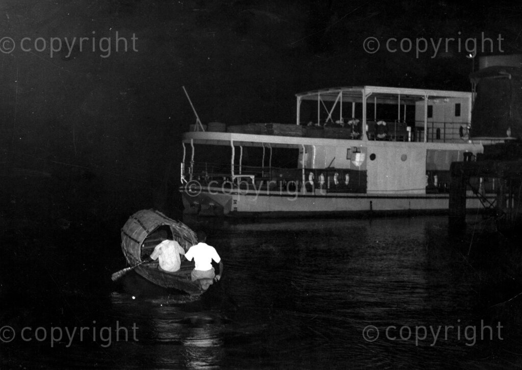 Nigeria's economic problem number one. Night operation, two smugglers rowing near a boat in the middle of the night so as to transfer contraband goods to their canoe.