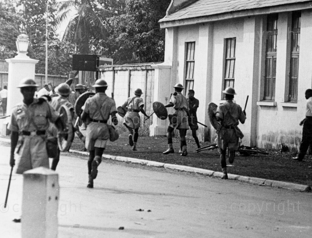 That Lagos Railway Riot. Shields raised, batons swinging, they charged crowd. The workers were not permitted to make for their destination. Baton-happy policemen charged them, hitting indiscriminately. It was tense, ugly there while it lasted. Men fell bleeding and groaning to ground. More defiant the rioters, tougher police became. Later, the rioters dispersed. In Lagos, railwaymen protested because certain high ranking job was not given to a Nigerian. They tried to get a note to the white boss whom they wanted to resign. The police charged with batons.