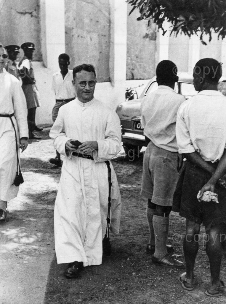 Death-cell message from Chief Obodo. A priest leaves the jail. The crowd senses he has been Father Confessor to the chief.
