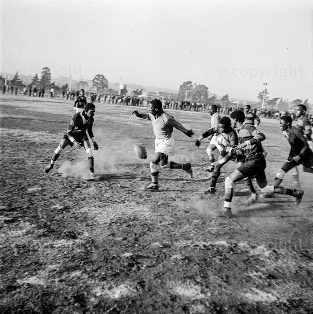 From left to right, Russel Ndziba, Village fly-half, waiting for the ball, November, Breakers' forward, rushing for the ball, Oliphant, Villagers' centre three-quarter passed the ball, and Rossett Ndziba rushing to support his man. Seven records broken at Athletic Championships. Scene in a thrilling senior division match between the Bugs, Johannesburg Bantu Football Association’s leading soccer team.