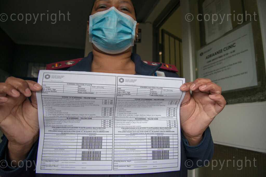 Clinic Manager Marilyn Jantjies holds up a screening sheet for TB and COVID-19 at the entrance of the Adriaanse Clinic in Elsies River, Cape Town, Monday, July 13, 2020. All patients are screened verbally for COVID-19 at the clinic door, and are asked to go to the hospital for a test if they screen positive. Although many health facilities in the area have experienced their health workers contracting COVID-19, Jantjies says nobody on her staff has yet taken ill. PHOTO: EVA-LOTTA JANSSON 